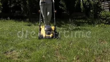 女孩正赤脚用黄色的割草机修剪一块凹凸不平的草坪